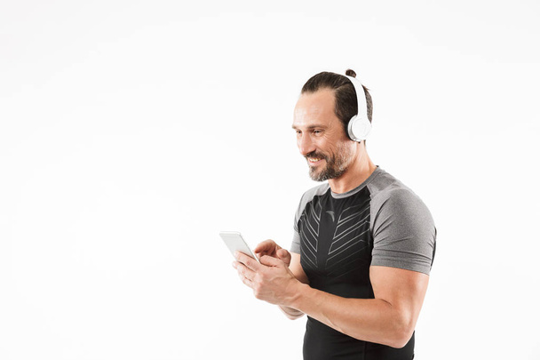 Portrait of a smiling mature sportsman listening to music - Photo, image