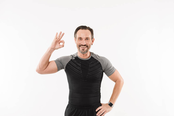 Portrait of pleased adult man fitness instructor smiling and ges - Φωτογραφία, εικόνα