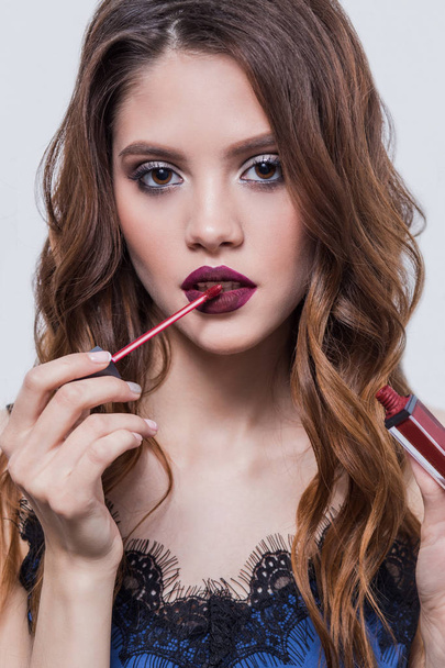Beautiful girl puts on the lips lipstick, lip gloss, close-up - Фото, изображение