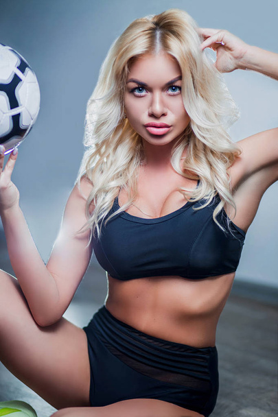 portrait of a girl, sexy beautiful blonde woman in black sports underwear, bra, breast, ball, with blue eyes, makeup, curls, white background, sports, crossfit, fitness, close-up - Φωτογραφία, εικόνα