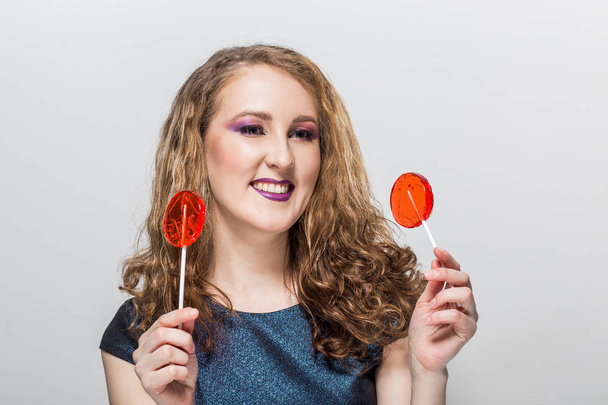 Happy girl holding a red round candy, laughs, smiles, positive emotion, - Fotoğraf, Görsel