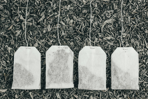 Bolsas de té de papel sobre té seco como fondo
 - Foto, Imagen