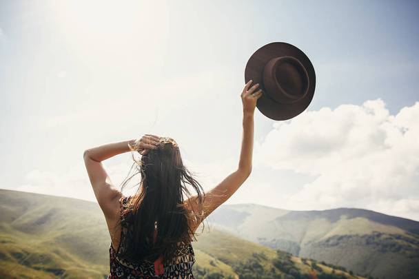 reizen en wanderlust concept. reiziger hipster meisje met hoed, kijken naar zonnige bergen. zomervakantie. ruimte voor tekst. geweldig sfeervolle moment. Gelukkige vrouw reizen - Foto, afbeelding