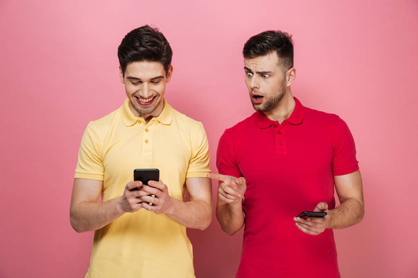 Portrait of a happy gay couple texting on mobile phones - Foto, immagini