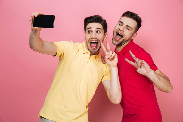 Portrait of a cheerful gay couple taking a selfie - Fotografie, Obrázek