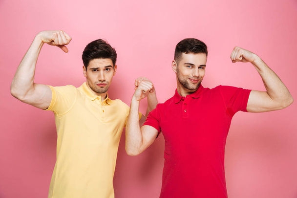 Portrait of a smiling gay couple flexing biceps together - 写真・画像