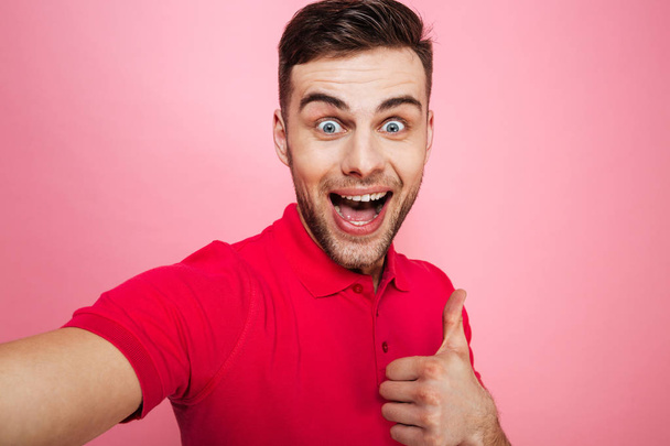 Portrait of a happy young man showing thumbs up gesture - Foto, Bild