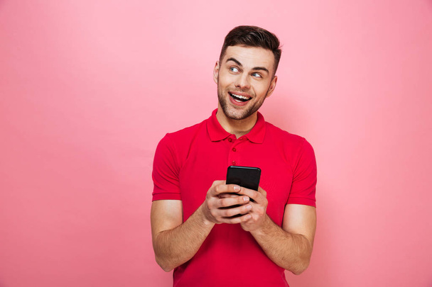 Portrait of a happy young man holding mobile phone - Foto, Bild