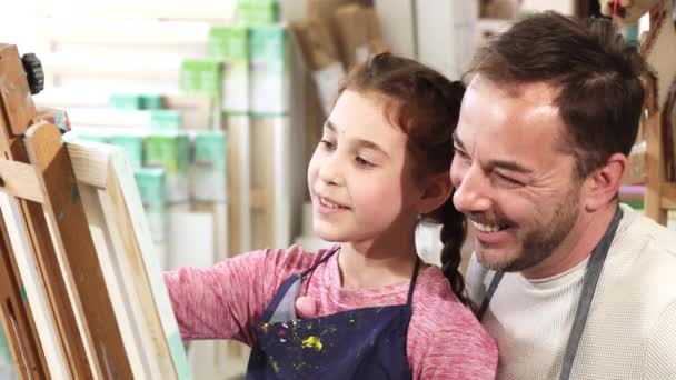 Iloinen isä ja tytär ottavat selfiet taidestudiossa maalauksen aikana
 - Materiaali, video