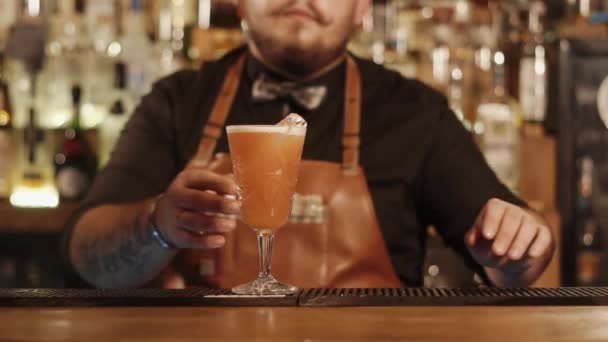Barman barbudo está se movendo de vidro com bebida mista para câmera à mão
 - Filmagem, Vídeo