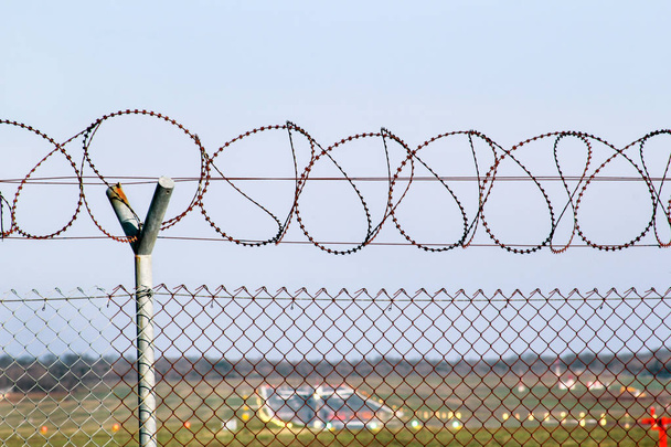 Bezpečnostní plot. Ochranné ostnatým drátem na letišti. Plot pletivo ostnatým drátem a betonové sloupy, letiště plot, oplocení kolem zakázané oblasti. - Fotografie, Obrázek