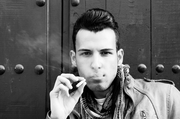 Portrait of an attractive young man smoking cigarette - Fotó, kép