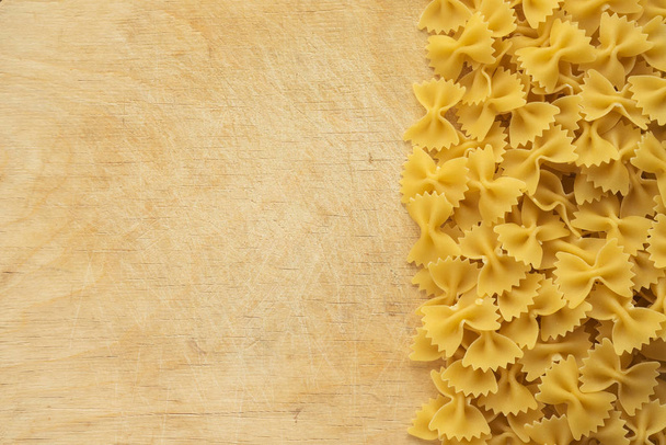 farfalle macaroni Beautiful laid out pasta with the right, side view on a wooden table top with a textured background. Close-up view from the top. Free space for text. - Photo, Image