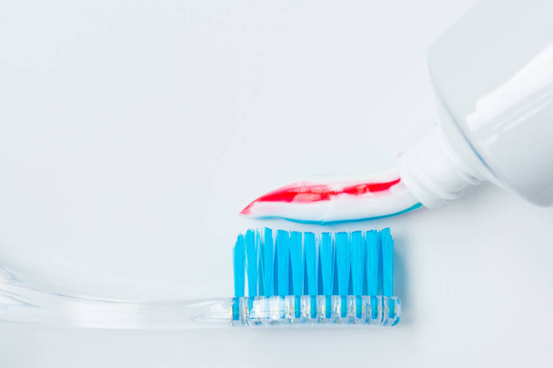 toothbrush of clear plastic with blue bristles, white blue red toothpaste squeezes out of a tube - Φωτογραφία, εικόνα