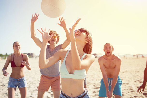 Gruppe von Freunden spielt am Strand beim Beachvolleyball - Foto, Bild