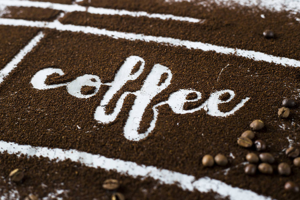 The word coffee is written on ground coffee next to coffee beans. Coffee Industry - Photo, Image