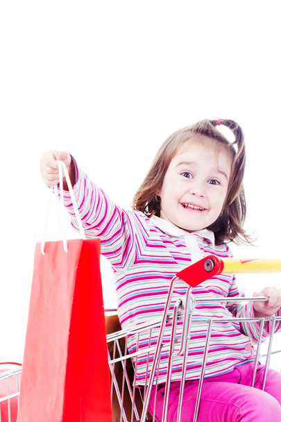 Kleines Mädchen im Einkaufswagen mit bunten Taschen - Foto, Bild