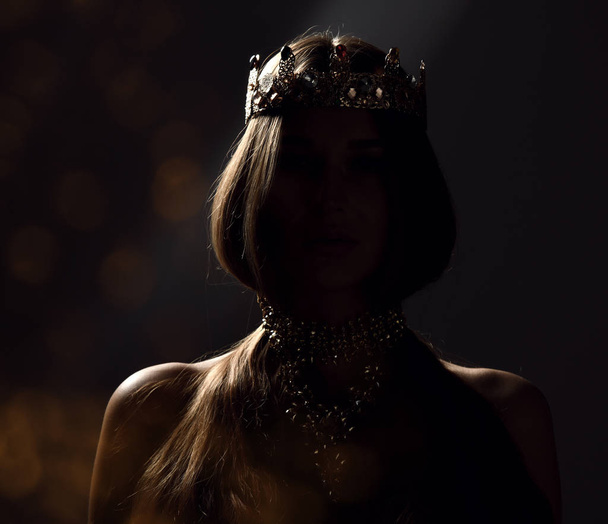 Beautiful sexy brunette beauty woman with long hair wear gold crown on dark background  - Foto, Bild