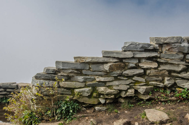 Bulutlu arka plan ile yığılmış taştan duvar - Fotoğraf, Görsel