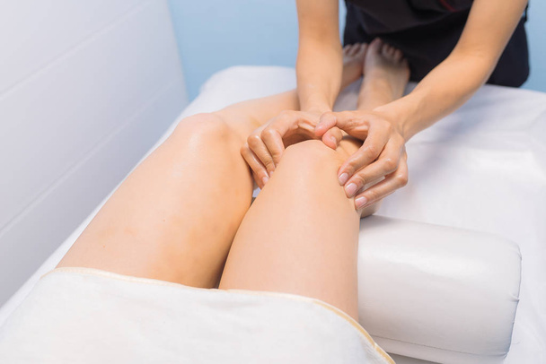 Фахівець робить масаж колін до клієнта мами
 - Фото, зображення