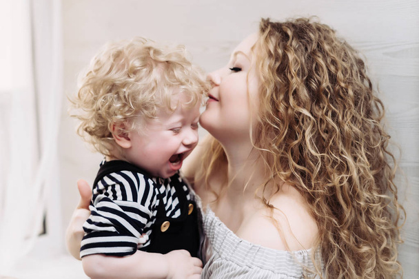 happy friendly family, curly mother holding her young son in her arms, laughing - Photo, Image