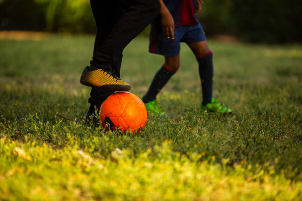 Dos niños pequeños que se divierten jugando un partido de fútbol en el soleado día de verano
 - Foto, Imagen