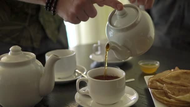 крупным планом руки людей, он наливает чай из чайника в чашки
 - Кадры, видео