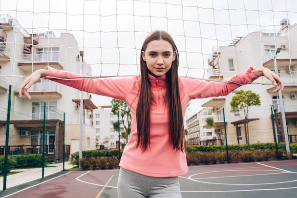 young long-haired girl exercising on an outdoor sports field, practicing fitness - Foto, Imagen