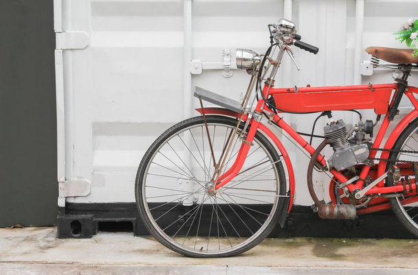 Vintage-Fahrrad rot, das Motor in der Nähe der Wand weißen Hintergrund hat - Foto, Bild