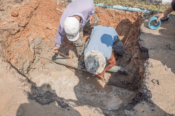 労働者は道路に大きな穴で水漏れを修正壊れた配管の脚ストンプを修復します。 - 写真・画像