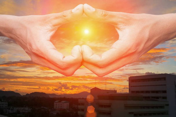 Hand, die eine Herzform mit Sonnenuntergangslicht bildet und Raum kopiert - Foto, Bild