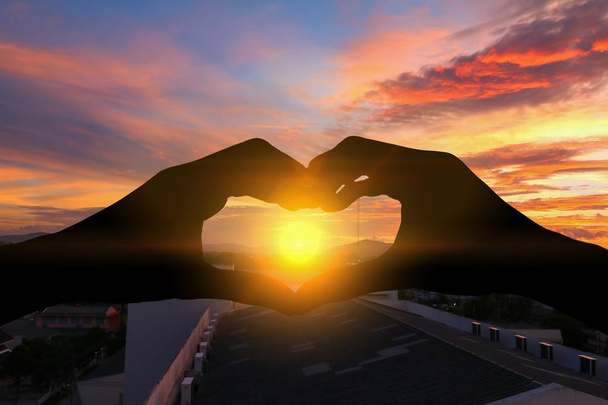 Hand formt Silhouette eine Herzform mit Sonnenuntergangslicht - Foto, Bild