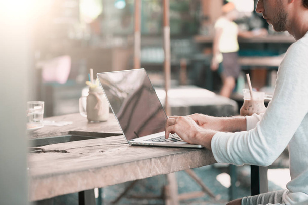 Jovem freelancer masculino sentado no café trabalhando no laptop
 - Foto, Imagem