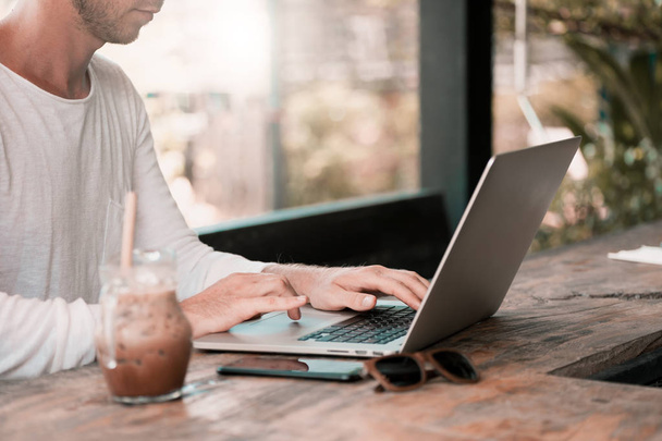 Młody mężczyzna freelancer, siedząc w kawiarni w laptopie - Zdjęcie, obraz