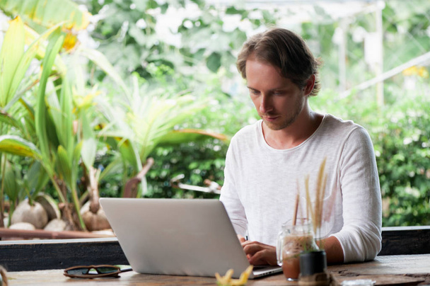 Young male freelancer sitting in cafe working in laptop - Photo, image