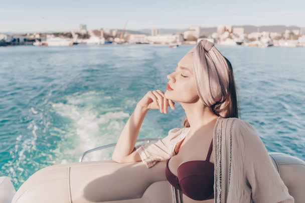a luxurious rich girl sails on her white yacht by the sea, enjoys the holiday and the sun - Photo, Image