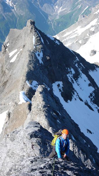ορειβάτης βουνών σε απόκρημνα και εκτεθειμένα ροκ κορυφογραμμή στο δρόμο του σε μια υψηλή κορυφή - Φωτογραφία, εικόνα