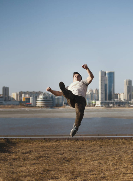 Young male parkour sportsman performs acrobatic jumps in front of skyline - Foto, afbeelding