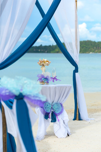 Стіл прикрашений келихами шампанського та морською раковиною. Підготовка до весілля на тропічному пляжі
. - Фото, зображення