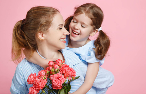 έννοια της ημέρα της μητέρας. μαμά και παιδί κορίτσι με το λουλούδι στο χρωματιστό backgroun - Φωτογραφία, εικόνα