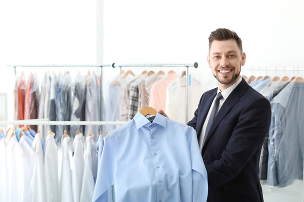 Young businessman holding hanger with shirt at dry-cleaner's - Photo, Image