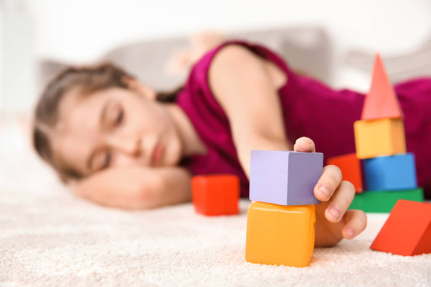 Little girl with autistic disorder playing at home, closeup of cubes - Fotó, kép