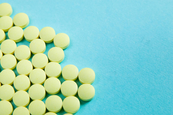 random yellow pills on blue isolated background - Foto, afbeelding