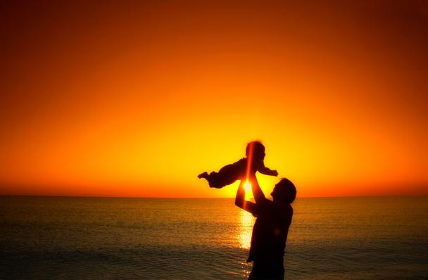 Vater und sein kleiner Sohn spielen am Strand bei Sonnenuntergang. Familienurlaub am Meer.  - Foto, Bild