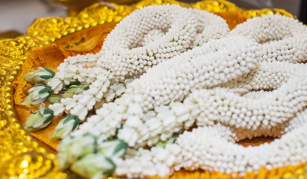 Тайские традиционные свадебные принадлежности, белая гирлянда из жасмина на золотистой дорожке
 - Фото, изображение
