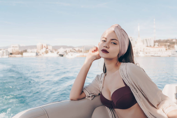 an attractive luxury girl with a headscarf on her head sails on her white yacht on the sea - Photo, Image