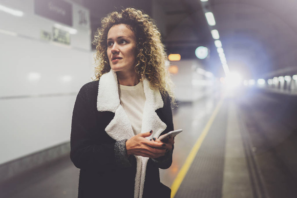 Pretty woman on commute transit using smartphone while standing in train station. Attractive girl happy using mobile phone app for conversation in holiday travel. - Fotografie, Obrázek