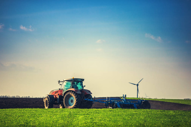 Farmer with tractor seeding crops at field - Photo, Image