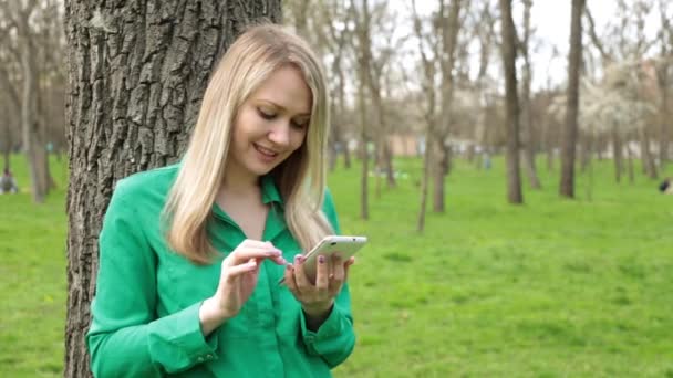 Woman using smartphone in a park - 映像、動画