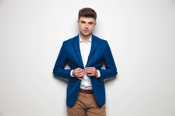 sexy inteligente hombre casual abotonando su chaqueta de traje azul
 - Foto, Imagen